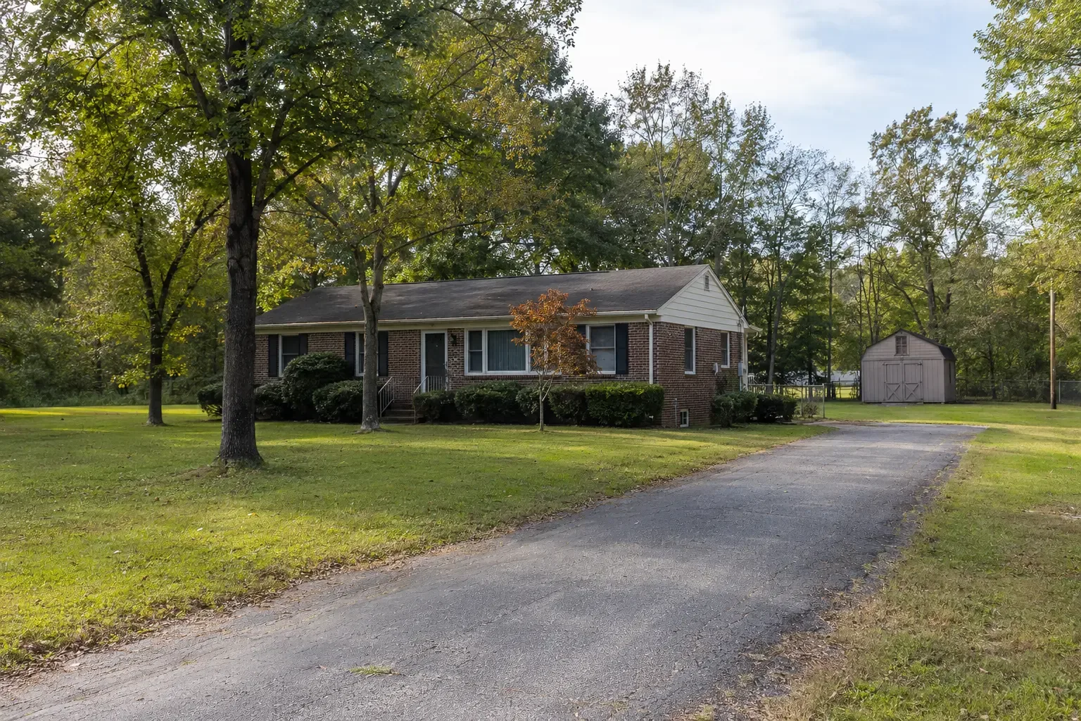 A home on a large green lot with a detached shed