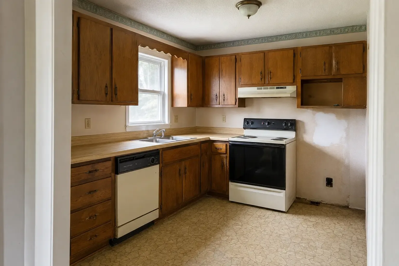 A dated kitchen with worn cabinets and unfinished wall repair