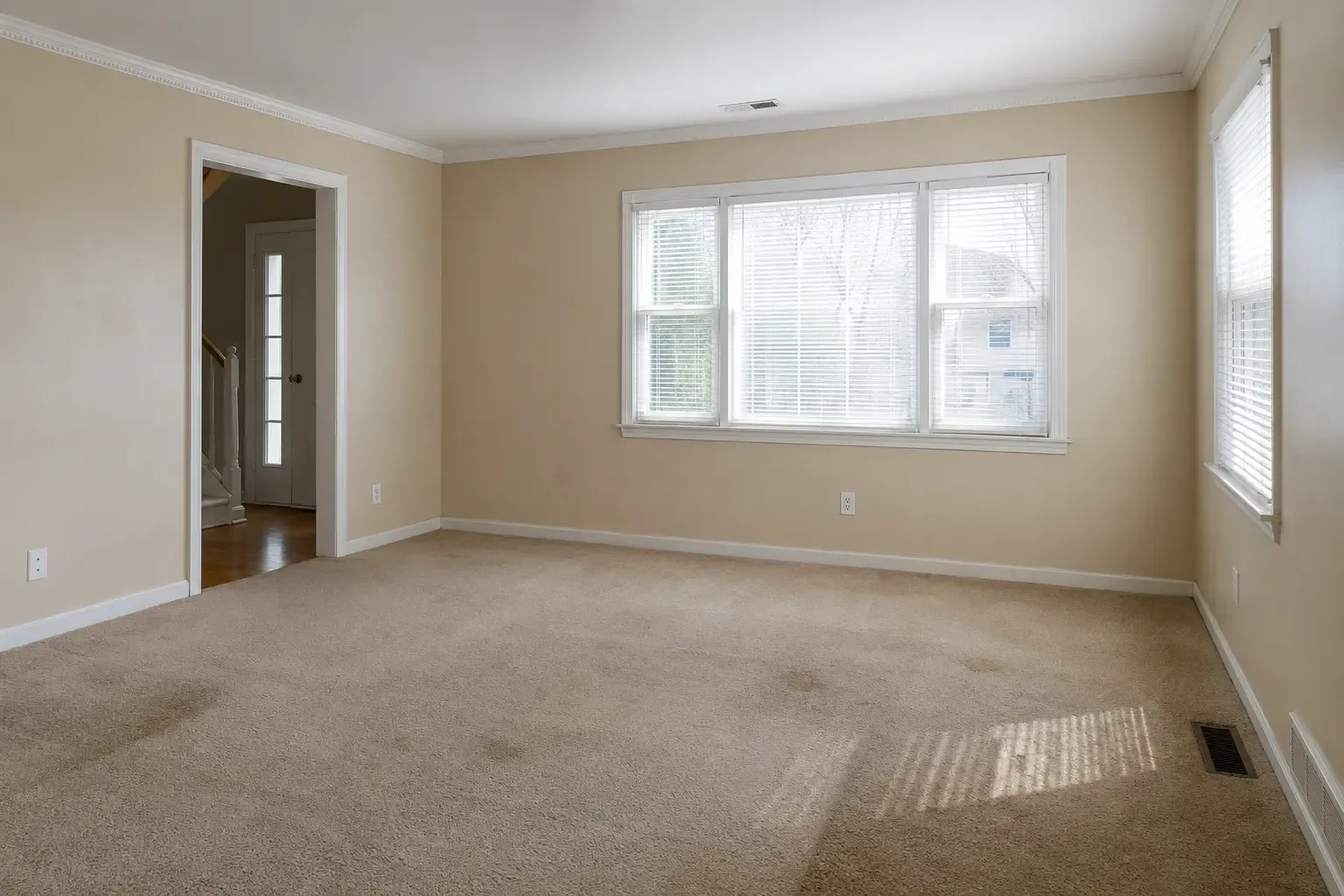 A clean but unstaged vacant living room with ordinary wear